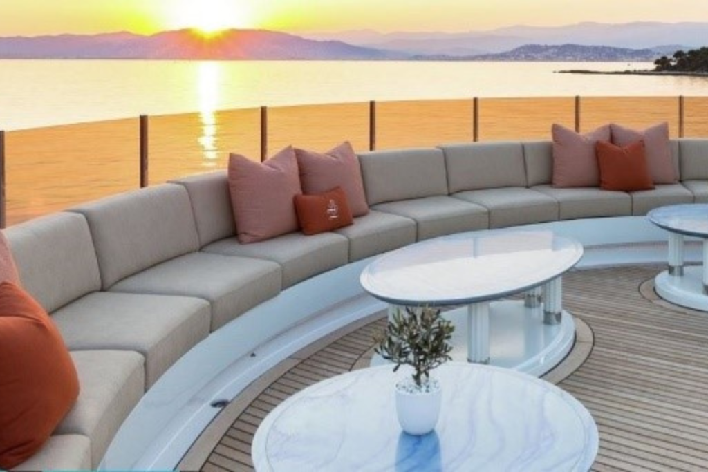 Image depicting taupe yacht upholstery beach seating with orange cushions and a ocean sunset