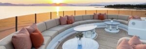 Taupe yacht upholstery seating with orange cushions and a ocean sunset