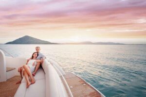 Superyacht guests on stern of superyacht sitting on outdoor upholstery