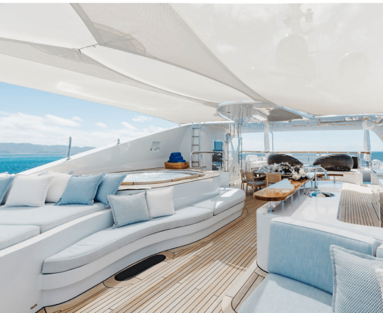 Fine exterior yacht furnishings and cushions with deck running between them towards a set table in the back