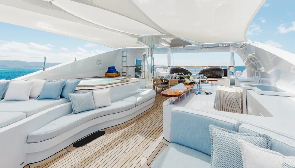 Fine exterior yacht furnishings and cushions with deck running between them towards a set table in the back