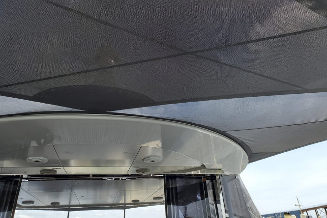 Mesh black sail awning providing shade attached to yacht.