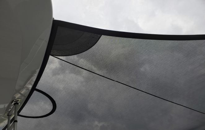 A black yacht sail awnings shading the yacht on a cloudy day.