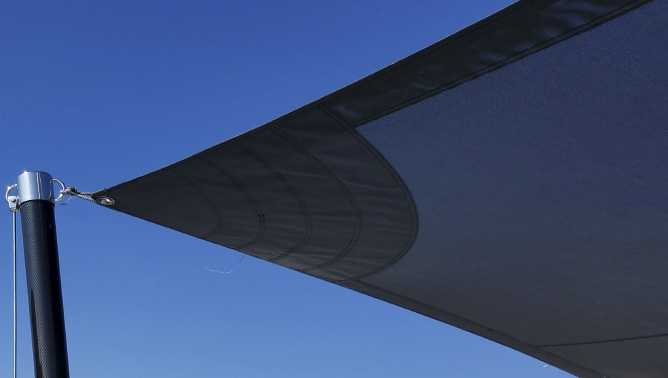 A black sail awning attached to a pole on a clear sky.