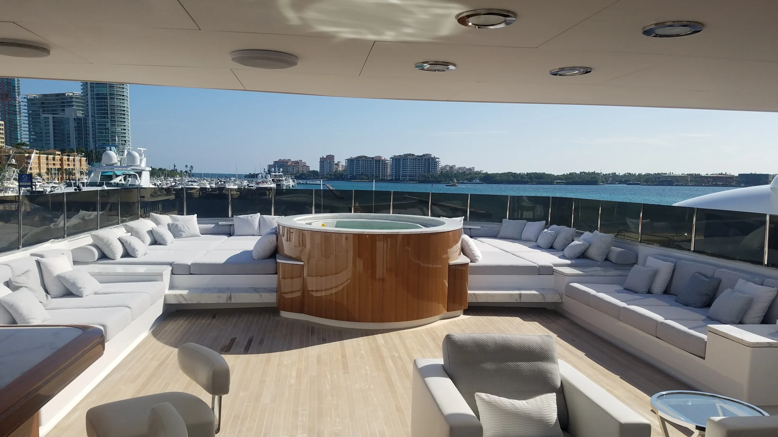Yacht exterior seating beside a jacuzzi, with the sun shining.
